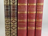 several old books are lined up in a row on a white surface