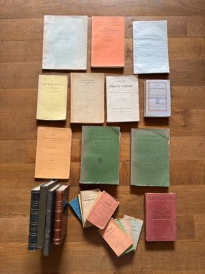 several books are arranged on a wooden floor next to a pile of papers
