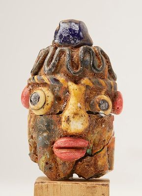 Une perle anthropomorphe en pâte de verre (restaurations).