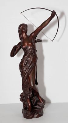 une statue antique en bronze représentant une femme avec un arc et des flèches