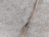 a gold chain with a black bead on top of it