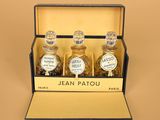 three bottles of jean patou in a box on a brown surface