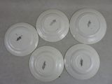 quatre assiettes blanches ornées de motifs, posées sur une table
