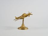 figurine d'avion dorée posée sur un socle, sur fond blanc