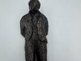statue d'un homme en costume-cravate, debout sur un bloc de bois