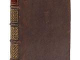 un vieux livre à la couverture brune posé sur une surface blanche