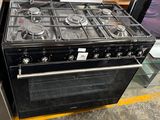 a black stove with four burners and a glass shelf