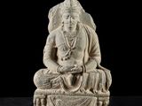 une statue blanche représentant une femme assise sur une table noire