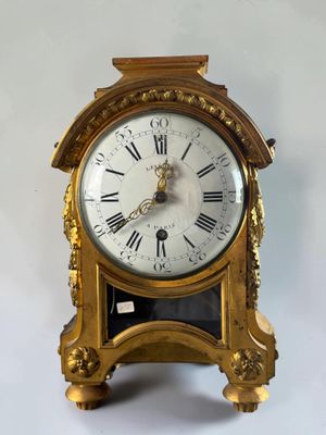 a gold clock with roman numerals on the face