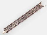 a close up of a silver bracelet with pink stones on it