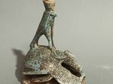 figurine of a man sitting on a rock with a hat on his head