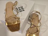 the gold sandals are next to a white box on the table