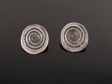 two silver earrings on a black surface with a black background