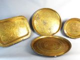 three brass trays and a plate on a white background