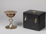 une boîte noire et une tasse argentée posées l'une à côté de l'autre