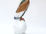 statue of a bird sitting on top of a rock on a white surface