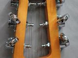 the headstock of a guitar with a wooden body on a gray surface