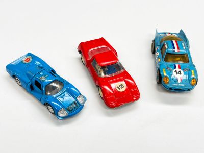 trois petites voitures sont alignées sur une surface blanche