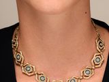 a close up of a woman wearing a necklace with blue stones on it