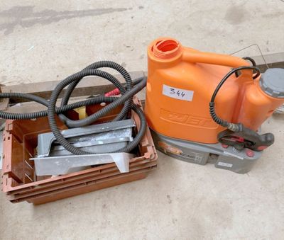 un pulvérisateur orange posé par terre à côté d'une caisse à outils