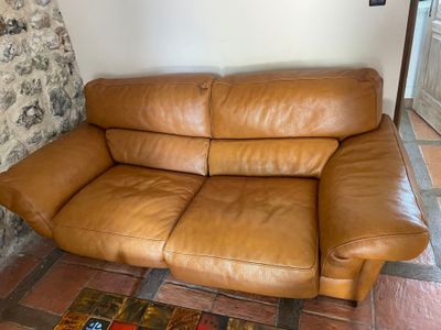 a brown leather couch sitting in front of a stone wall