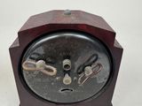 a small wooden clock with a metal face on a white surface