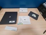 une table sur laquelle se trouvent un ordinateur portable, un clavier, une souris et d'autres objets