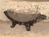 a silver bowl sitting on a stand in front of a stone wall