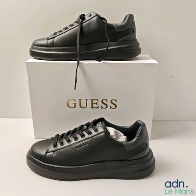 un gros plan sur une paire de chaussures noires posées sur une boîte blanche