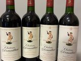 quatre bouteilles de vin rouge sont alignées sur une table