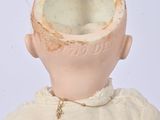 a small doll with a broken head sitting on a chair
