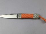 a small knife with an orange handle on a table