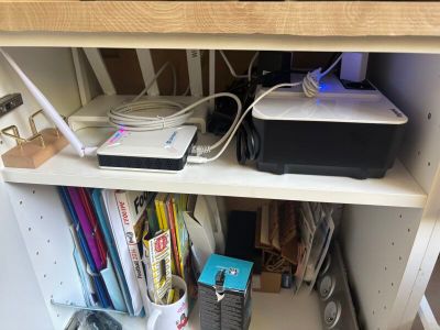 a computer and printer on a shelf in the corner of a room
