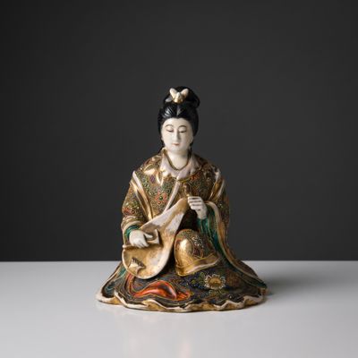 a chinese figurine of a woman playing a musical instrument