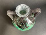 a green and white vase with a handle on a table