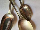 two silver spoons hanging from a hook on the wall