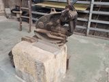 une statue représentant un homme tenant un marteau sur un bloc