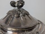 an antique silverplated teapot with a bird on top of it