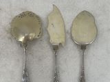 three silver spoons and a knife on a white surface