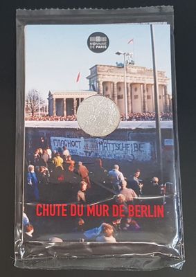 a silver coin with a picture of a crowd in front of a building