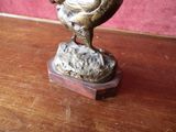 a bronze statue of a rooster on a wooden table
