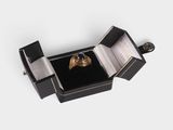 a black box with a ring inside of it on a white surface