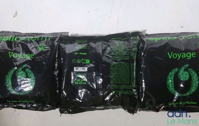 trois sacs noirs portant une inscription verte, posés sur une table