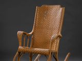 un fauteuil à bascule en bois avec une assise en osier, sur fond gris