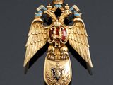 an image of a gold eagle broochle with blue and red stones
