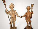 two statues of a boy and a girl holding hands on a pedestal