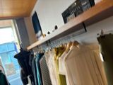 many shirts hanging on a rack in a room