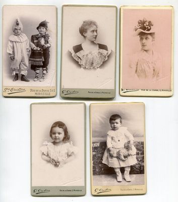 plusieurs vieilles photos d'enfants en robe et chapeau, posant sur un fond blanc