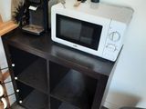 a microwave sitting on top of a shelf next to a chair