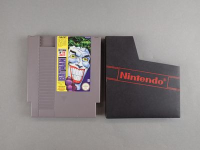Un vieux jeu Nintendo est posé sur une table, à côté d'une boîte.